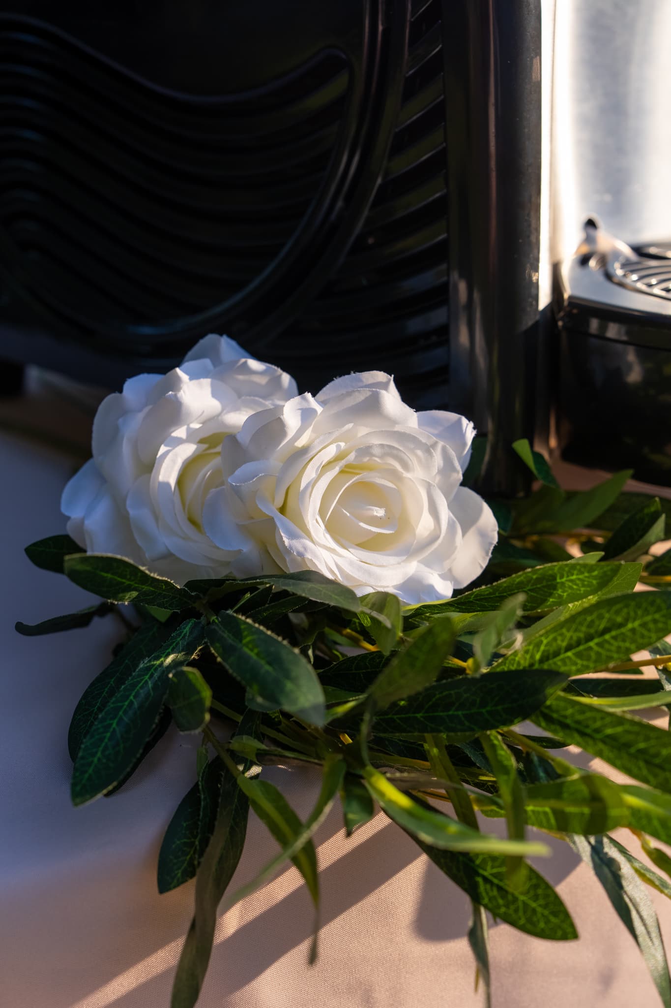 White rose and greenery resting against the twin-barrel machine at golden hour